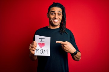 Young african american man holding love mom message paper celebrating mothers day very happy pointing with hand and finger