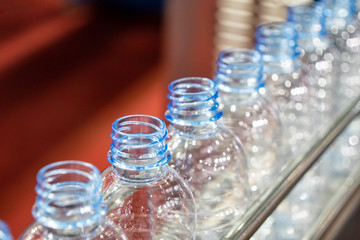 The PET bottles in the rail on the conveyor belt for filling process in the drinking water factory. The drinking water factory production process by automatic filling machine in the plant.