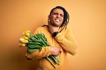 Young african american afro romantic man with dreadlocks holding bouquet of yellow tulips Touching painful neck, sore throat for flu, clod and infection