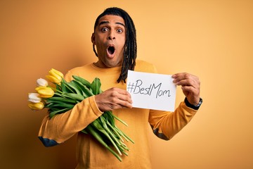 African american man holding best mom message paper and tulips celebrating mothers day scared in...