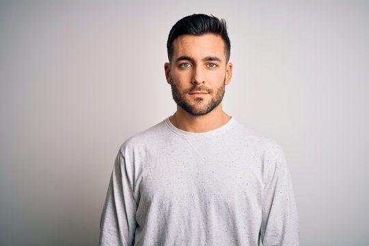 Young handsome man wearing casual t-shirt standing over isolated white background with serious expression on face. Simple and natural looking at the camera.