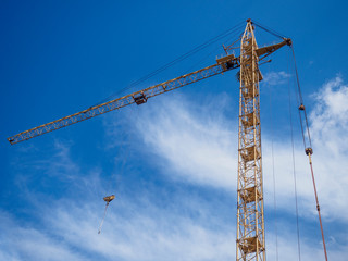 High-rise construction crane. Metal device is yellow. Concept of construction equipment.