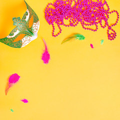 Mardi gras card flat lay on bright yellow background, top view, copy space. Frame with traditional Mardi gras beads, masks, feathers flat. Carnival holiday concept overhead