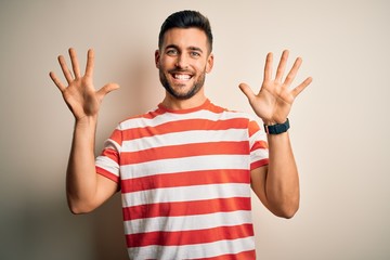 Young handsome man wearing casual striped t-shirt standing over isolated white background showing...