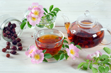 Cup and teapot tea with hip rose flowers