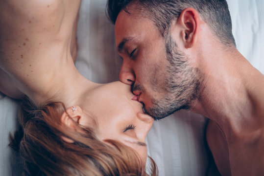 Beautiful couple in love having a romantic kiss on the bed at home. 