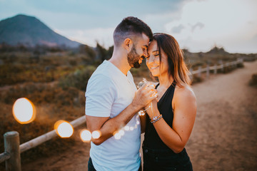 couple put their heads together while holding beautiful LED lights in nature