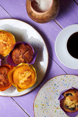 Top view on sweet muffins cupcakes and cup of coffee on purple desk