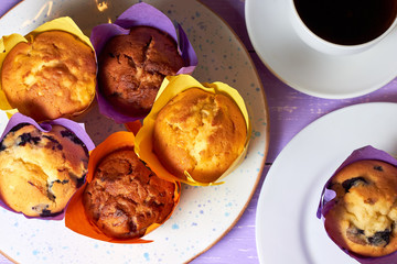Top view on sweet muffins cupcakes and cup of coffee on purple desk