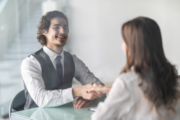 Friendly smiling businessman and businesswoman handshaking over the office desk after pleasant talk and effective negotiation, good relationships. Business concept photo