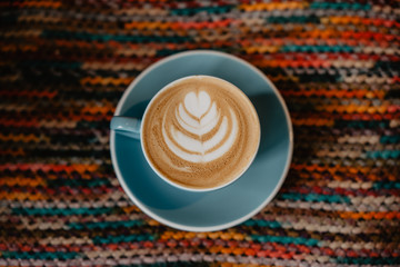 Taza de Café con leche azul con latte art en fondo de colores