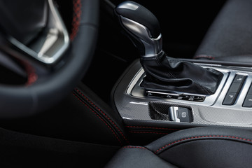 Selector automatic transmission with leather in the interior of a modern expensive car. The background is blurred. Black leather car interior. Luxurious car instrument cluster. Close up shot