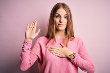 Young beautiful redhead woman wearing casual sweater over isolated pink background Swearing with...