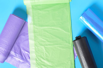 Scattered rolls of disposable plastic garbage bag on blue background. Top view. Close-up