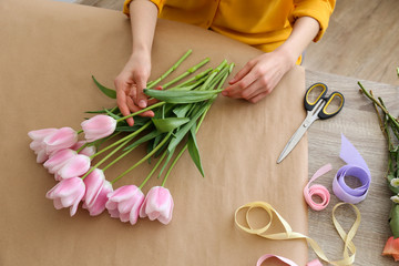 Unrecognizable young woman wearing mustard yellow shirt making a beautiful bouquet of flowers. Female florist at work concept. Close up, copy space, background.
