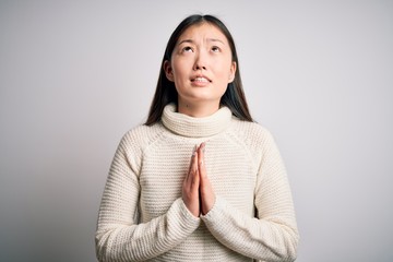 Young beautiful asian woman wearing casual sweater standing over isolated background begging and...