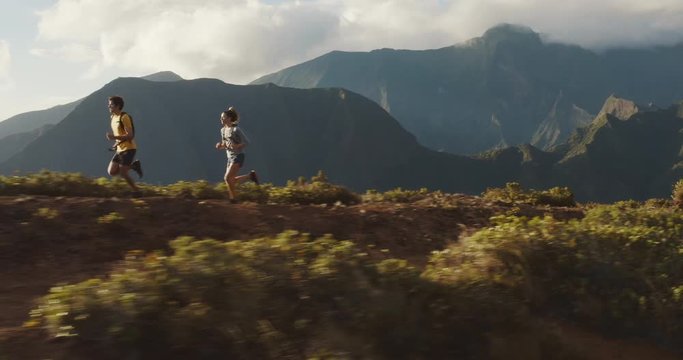 Aerial view of two runners exploring a mountain ridge at sunset, young man and woman running together outdoors, ultimate freedom running concept