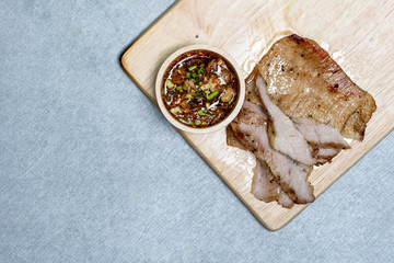 Slice grilled pork with fish sauce on wooden plate or table. Top view.