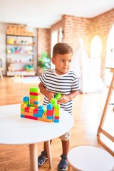 Beautiful toddler boy playing with construction blocks at kindergarten