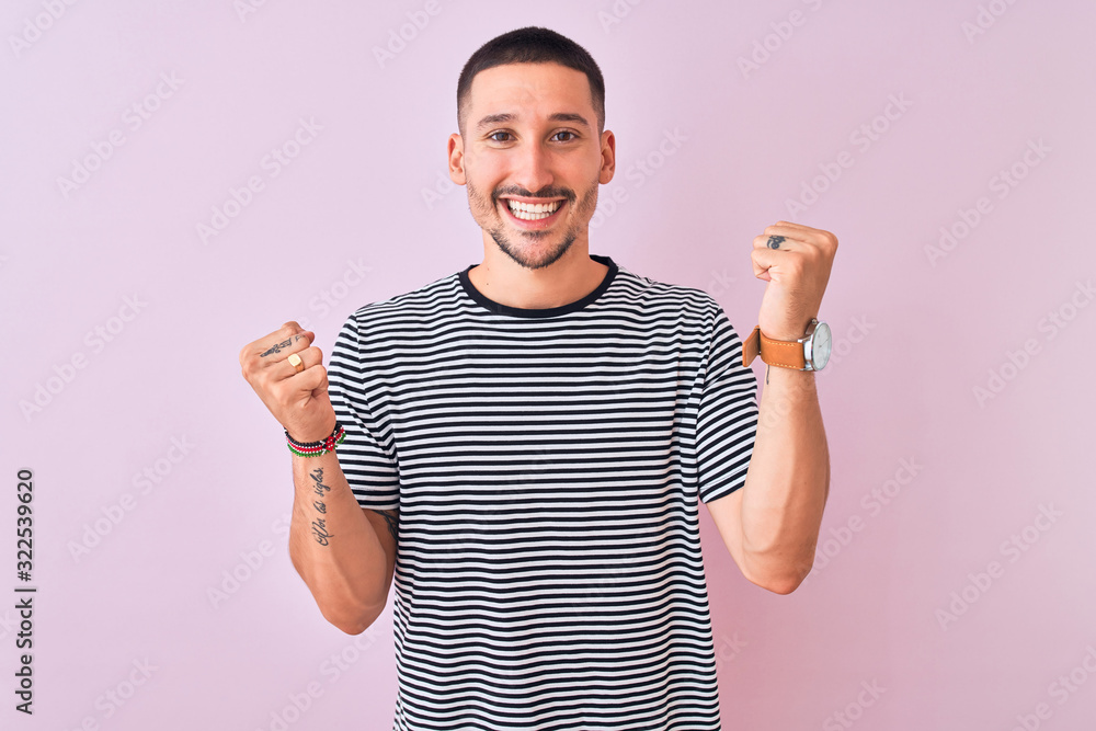 Sticker young handsome man wearing striped t-shirt standing over pink isolated background celebrating surpri