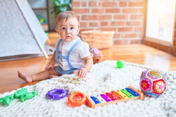 Beautiful toddler sitting on the blanket at kindergarten