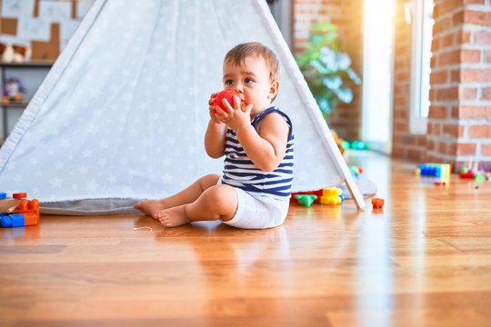 Adorable toddler playing around lots of toys at kindergarten