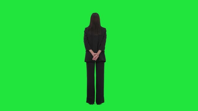 Back view of interested business woman in suit at attention watching and learning seminar as spectator. Full length on green screen background.