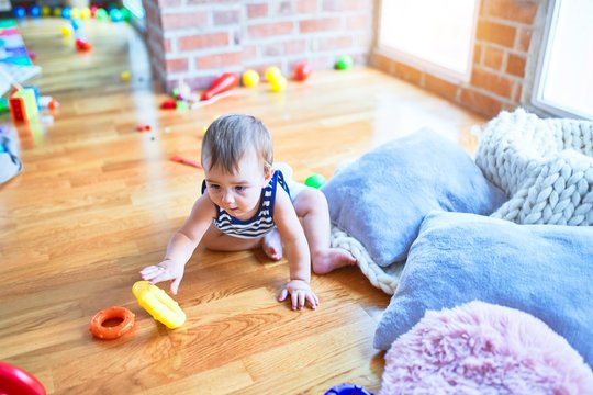 Adorable toddler crawling around lots of toys at kindergarten