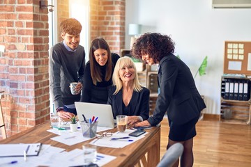 Group of business workers smiling happy and confident. Working together with smile on face  using laptop at the office