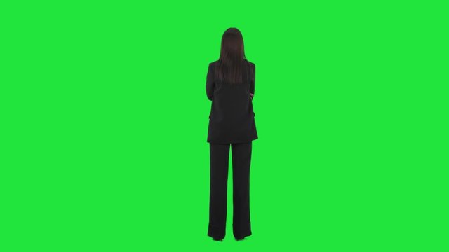 Back view of young business woman looking and turning around deciding between choices. Full length on green screen background.