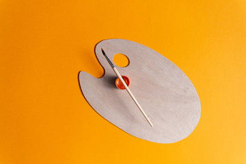 Artist brush and paint on wooden clean palette on orange background