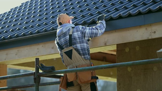 Roofing Industry. Ceramic Tiles House Roof Construction. Contractor Worker on Scaffolding.
