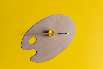 Artist brush and paint on wooden clean palette on yellow background