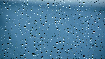 Crystal clear water drops on the window with blue background; raindrops on the window