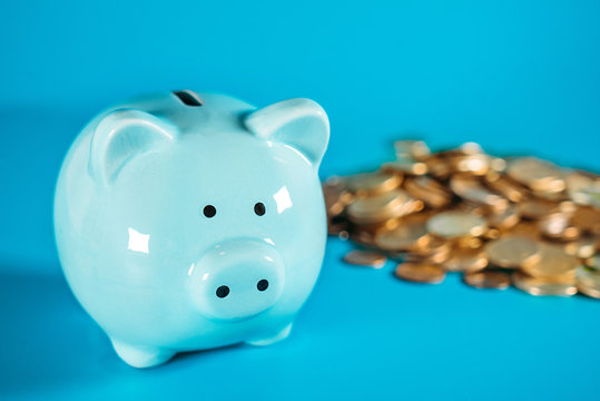 Horizontal image of a blue piggy bank standing on a white desk surface with copy space on the background.