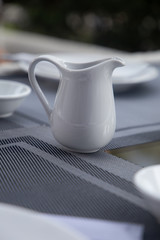 White jug on old wooden table over table background
