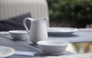 White jug on old wooden table over table background