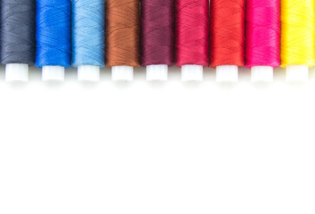 Spools with threads of different colors for embroidery and needlework. Lie in a row on a white isolated background. Multi-colored threads for hobbies and sewing.