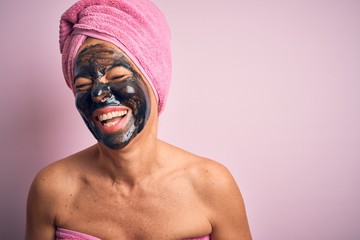 Middle age brunette woman wearing beauty black face mask over isolated pink background smiling and laughing hard out loud because funny crazy joke with hands on body.