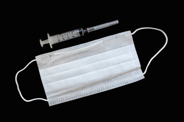 Surgical masks rubber ear straps. Syringe and medicine for the disease. mask on a black background. a respiratory mask containing a positive blood test result for a new coronavirus is spreading 