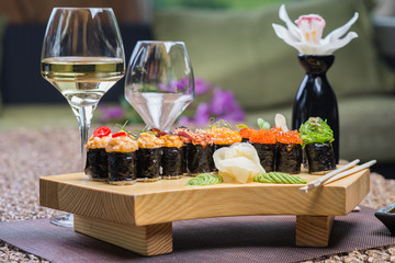 Set of several different rolls on a wooden stand on a table in a Japanese restaurant. Japanese traditional sushi and rolls.