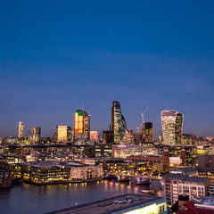 Fototapeta na wymiar City of London at dusk. An elevated view of the illuminated financial district skyline fronted by the River Thames riverside.