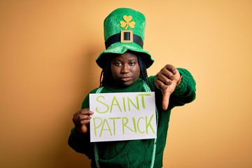 Plus size african american woman wearing green hat holding banner on saint patricks day with angry...