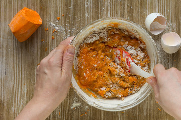 Woman hands mixing batter for carrot pie on the wooden background