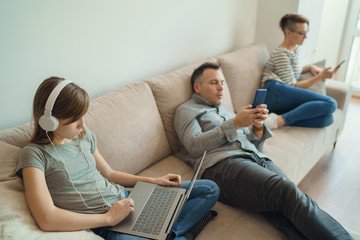 Technology addicted family: parents and child use laptop and mobile phones. Modern family values -...