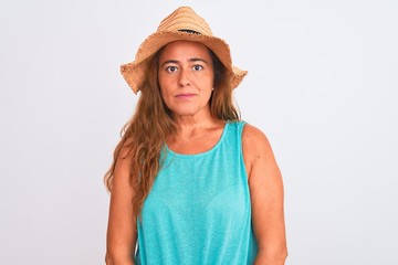 Obraz na płótnie Canvas Middle age mature woman wearing summer hat over white isolated background with serious expression on face. Simple and natural looking at the camera.