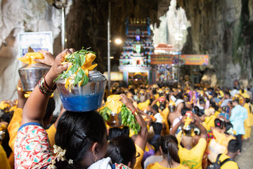 Hindu devotees entering Batu Caves during Thaipusam festival in Kuala Lumpur, Malaysia. Selective focus on woman on the left. Bokeh effect.