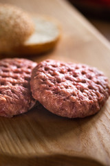 Buns, raw beef cutlets, tomatoes and herbs for burgers cooking