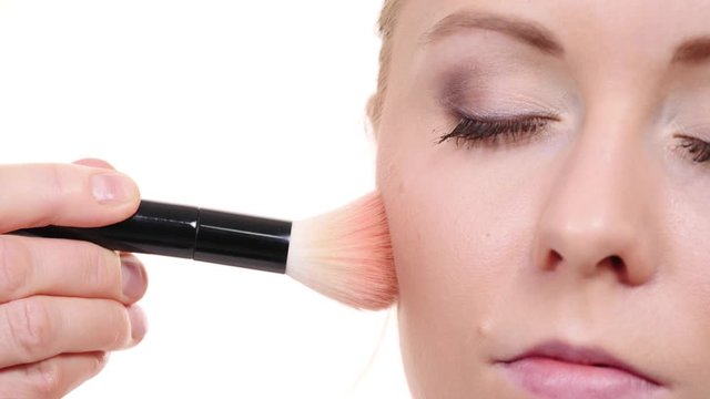 Woman face painting. Makeup artist applying blush bronzer with brush to model cheek. Cosmetic beauty procedures and makeover concept.  Slow motion