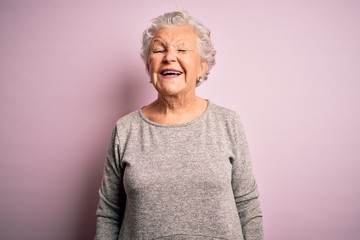 Senior beautiful woman wearing casual t-shirt standing over isolated pink background winking...